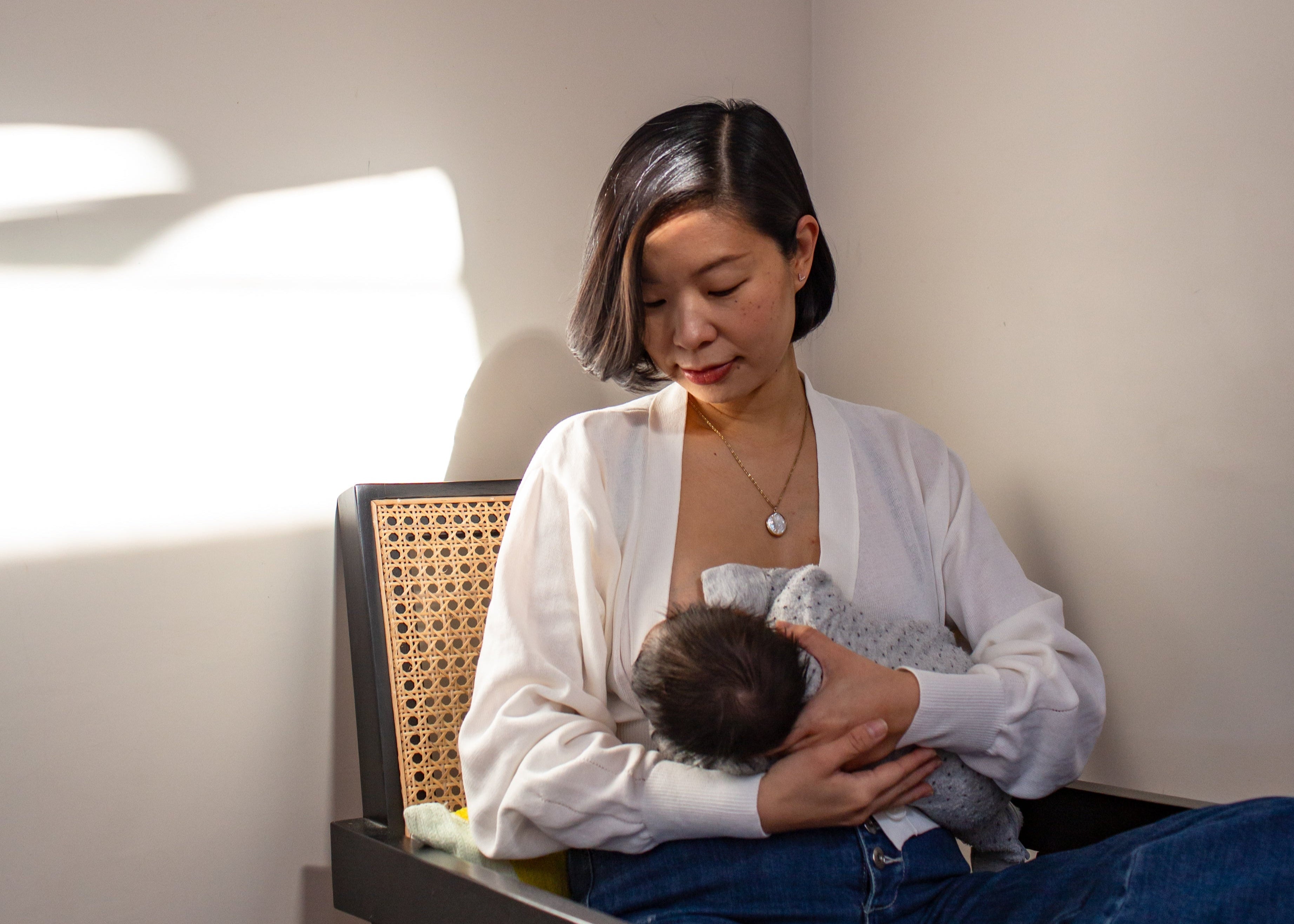 Woman sitting on a chair holding a baby in a room with a map on the wall.